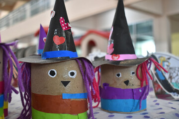 Colorful handmade witch crafts made from recycled materials, featuring paper hats and yarn hair, displayed on table
