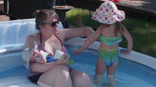 Mother Applying Sun Screen To Her Kid In the Pool