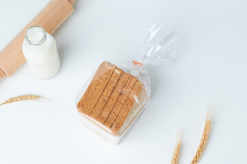 Freshly Baked Bread and Milk Arranged With Wheat on a White Surface
