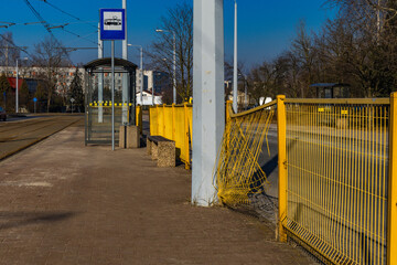 Road accident scene, damaged net at the bus stop, car hit the fence, yellow net protecting pedestrians at the bus stop bent