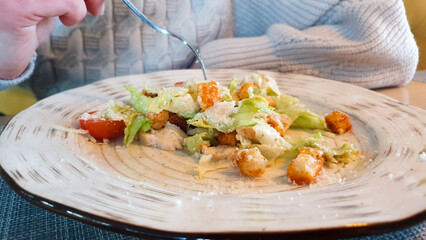 Caesar salad. Girl eating vegetable salad from a plate in a restaurant.