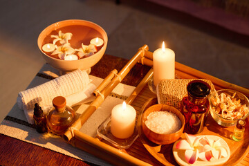 High angle shot of wooden tray with cosmetic products, aroma candles and dried flowers on coffee table