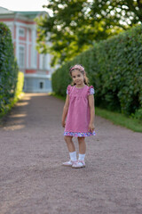 Young caucasian girl in pink dress smiling on garden path outdoors