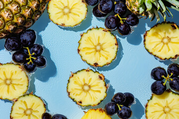 A pattern of floating fruit slices--bananas, pineapples, and grapes--against a bright blue sky
