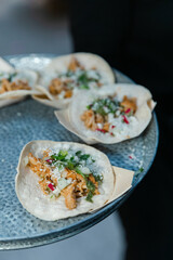 Delicious tacos served on a decorative plate at a vibrant outdoor gathering in a bustling city in the evening