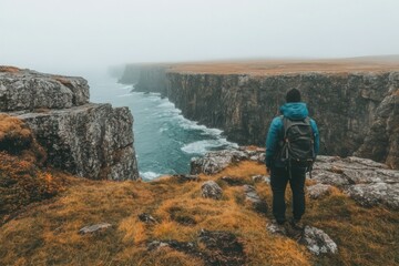 Fototapeta premium Hiker on Foggy Coastal Cliff Overlooking Ocean