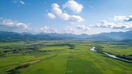 Lush Green Valley Landscape with River and Mountains Under Blue Sky
