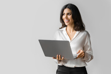 Young middle eastern businesswoman using laptop pc ai application for work isolated on white wall. Indian or arabic woman it specialist in business clothes holding computer, doing data base research