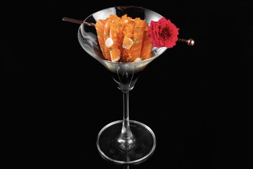 Delightful dessert served in martini glass, featuring vibrant orange layers, garnished with flower and nuts, perfect for special occasions