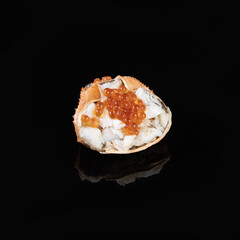 Fresh crab shell with orange roe on black background, showcasing delicate texture and vibrant color of seafood
