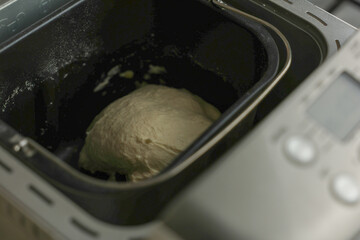 In the black bowl of the automatic bread machine there is dough, you can see the cooking panel. The concept of kneading dough, making bread. High quality photo