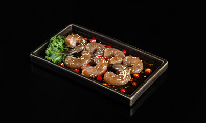 Delicious shrimp dish served on black plate with sauce, garnished with greens and red chili. Perfect for seafood lovers and culinary enthusiasts