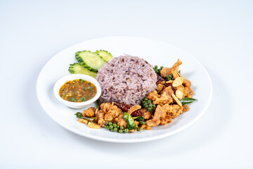 Delicious plate of purple rice with fried chicken, spicy sauce, and fresh vegetables. vibrant and flavorful dish that showcases mix of textures and tastes