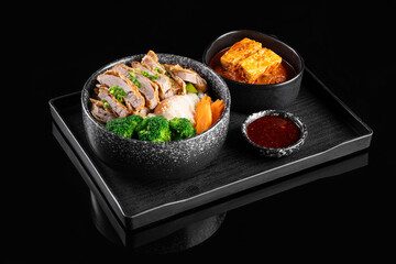 Delicious Asian cuisine featuring sliced chicken, broccoli, carrots, and tofu on black tray, creating visually appealing meal