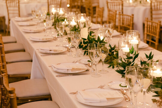 Elegant dining setup with candlelight and greenery for a special occasion in a beautifully decorated venue