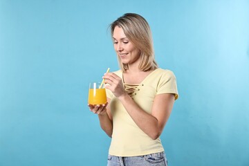 Woman with glass of orange juice on light blue background. Refreshing drink