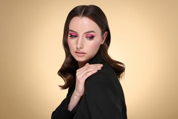 Portrait of beautiful young woman with stylish makeup and gorgeous hair on beige background
