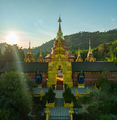 Naklejka premium aerial view of the golden gate with intricate golden architecture at Phra Yai Wat Phra That Doi Phra Chan (Daibutsu) temple..A stunning view of a traditional temple surrounded by lush greenery