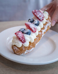 Person is holding a pastry with strawberries and blueberries on top