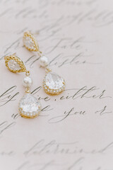 Elegant crystal earrings displayed on decorative paper with beautiful handwriting in a bright setting