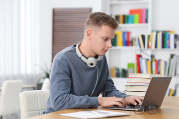 Student preparing for exam with laptop at table indoors