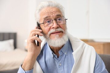 Handsome bearded man talking on smartphone indoors