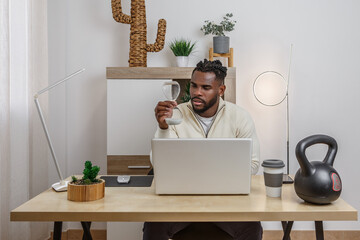 Remote work setup featuring an African American man with a laptop, engaged in focused concentration...