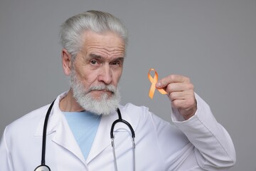 Multiple Sclerosis awareness. Doctor with orange ribbon on grey background