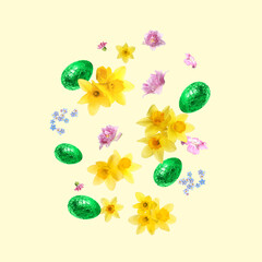 Chocolate eggs wrapped in bright foil and beautiful spring flowers in air on beige background