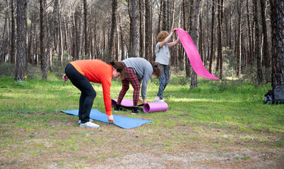 Senior Caucasian women setting up yoga mats in a forest for an outdoor class