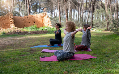 Mature women practicing seated yoga in a peaceful forest, engaging in breathing exercises and mindfulness near ancient ruins