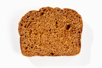 Slice of fresh dark bread on white background in sunlight close up