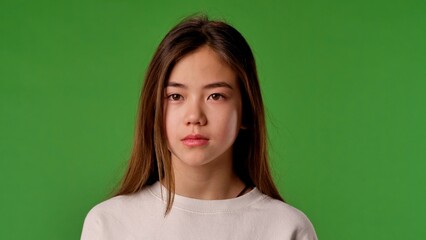 Obraz premium Asian girl child in shirt standing looking at camera, neutral expression, isolated on chroma key green screen studio background mockup.