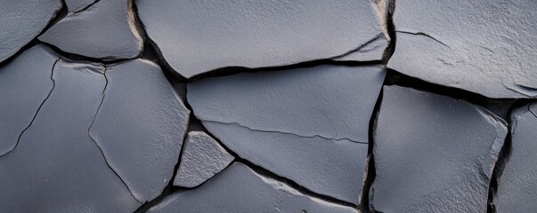 Close-up view of a dark asphalt surface showcasing intricate cracks and variations in texture. This background is ideal for design projects providing ample copy space for text overlays
