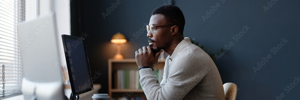 Fototapete website header shot of thoughtful black office worker using desktop computer at working desk against