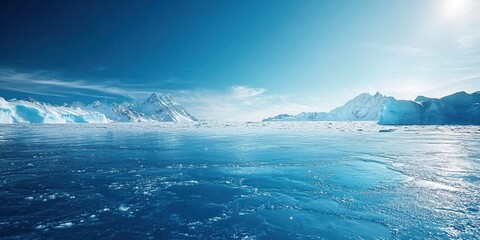 Fototapeta premium A wide shot of the frozen Ocean with icebergs in the distance, a clear blue sky, the sun shining down on the water