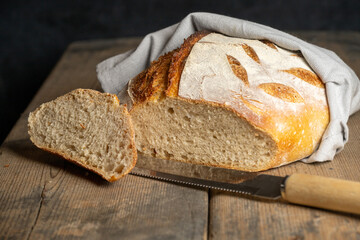 A cut homebaked artisan sourdough bread with a slice cut of and a breadknife. 