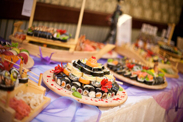 Elegant sushi catering display with a variety of fresh and gourmet rolls. Exquisite Japanese cuisine served on a stylish buffet table for a banquet. Wedding party finger food.