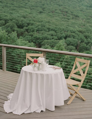Cozy outdoor dining setup on a deck overlooking lush green landscape at sunset