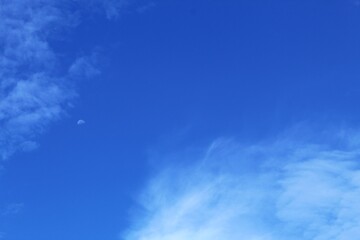 The morning blue sky is decorated with white clouds and the moon is still visible.