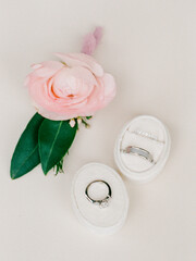 Elegant wedding rings displayed with a delicate pink flower in a serene setting before a special ceremony