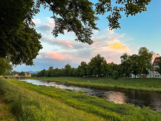 River runs through a grassy area with trees in the background