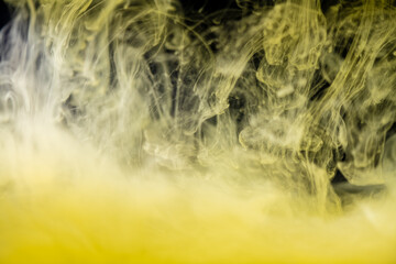 clouds of yellow smoke on a black background, clouds of paint in water, aquarium, abstract background, texture
