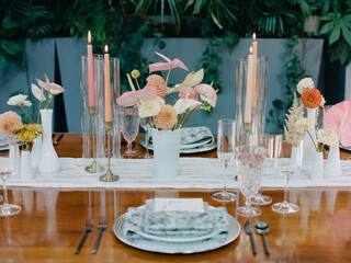 Elegant dinner table setting with floral arrangements and candlelight in a lush indoor garden