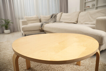 Stylish wooden coffee table near sofa in living room, closeup