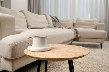 Cup of drink on stylish coffee table near sofa in living room