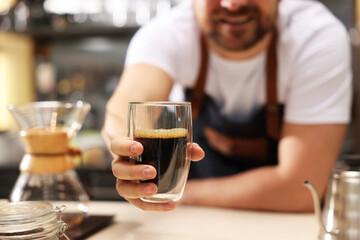 Barista suggesting cup of aromatic filter coffee in cafe, closeup. Selective focus