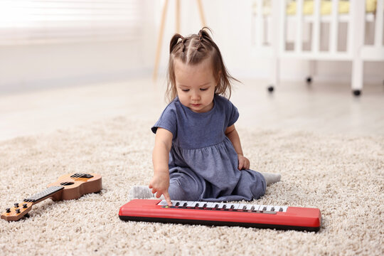 Cute little girl playing with toy piano at home