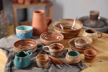 Different beautiful pottery and set of clay crafting tools on wooden table indoors