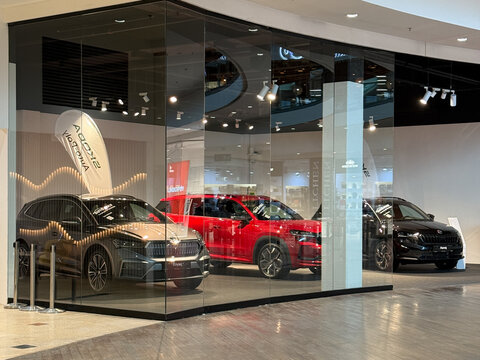 Prague, Czech republic - January 28, 2025: Modern Skoda showroom inside Harfa shopping center in Prague. Glass walls reflect bright lighting, showcasing three displayed cars in a sleek interior. 